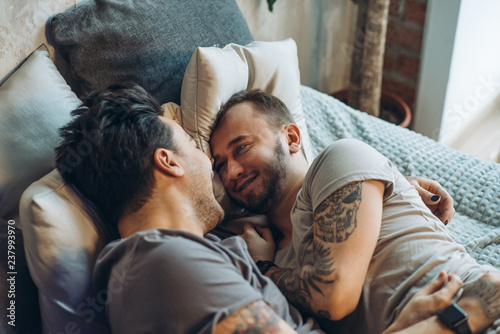 Close-up of happy gay couple sleeping in bed together. Enjoying the company of each other. Comfort and relaxation. photo