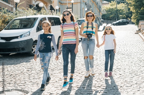Mature woman with children walking on a city street on summer sunny day