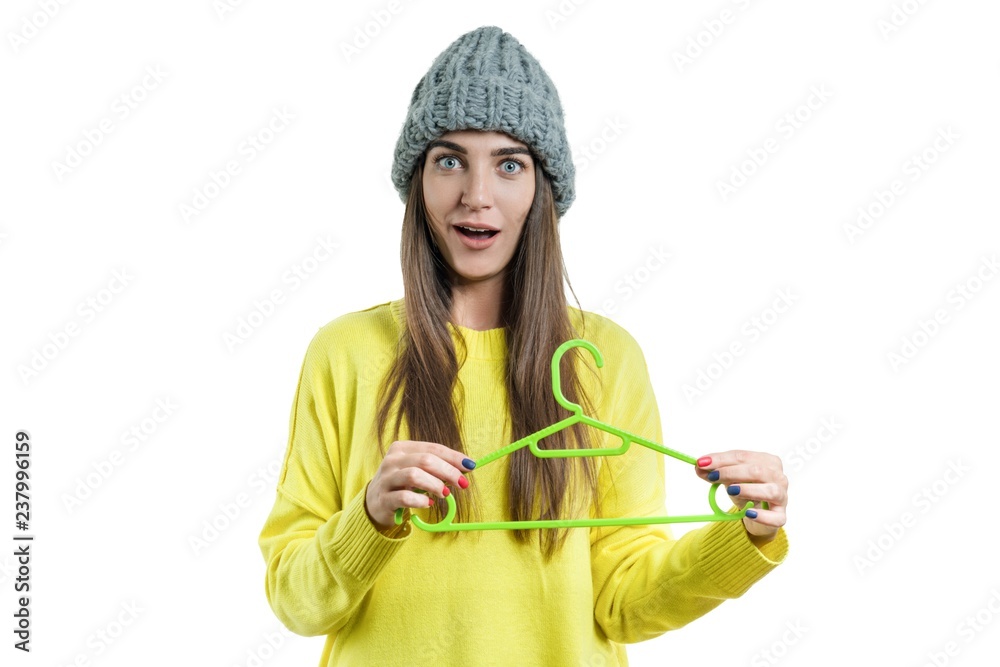 Beautiful emotional young woman with empty clothes hanger, autumn winter season, girl in sweater and knitted hat, isolated on white background Beautiful emotional young woman with empty clothes hanger, autumn winter season, girl in sweater and knitted hat, isolated on white background