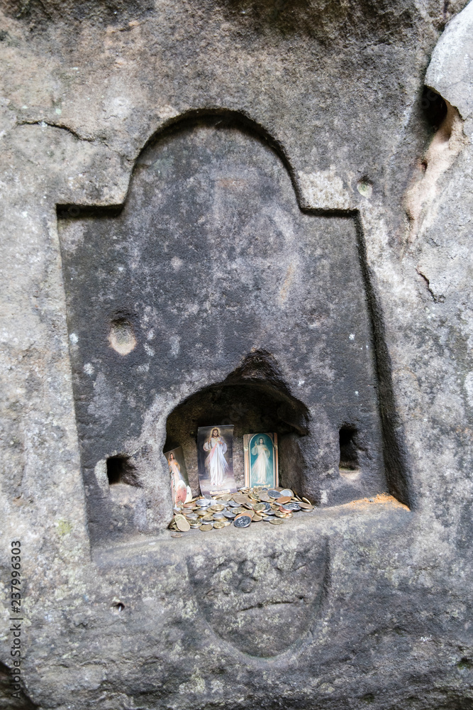 Coins in a rock niche with religious pictures of saints. Coins in a rock niche with religious pictures of saints.