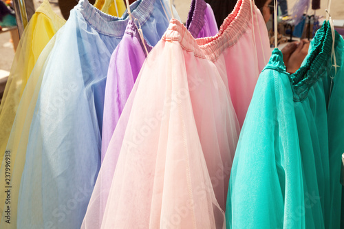 Row of hanging colorful gauze skirts at a clothing store. Brightly colored performance costumes background