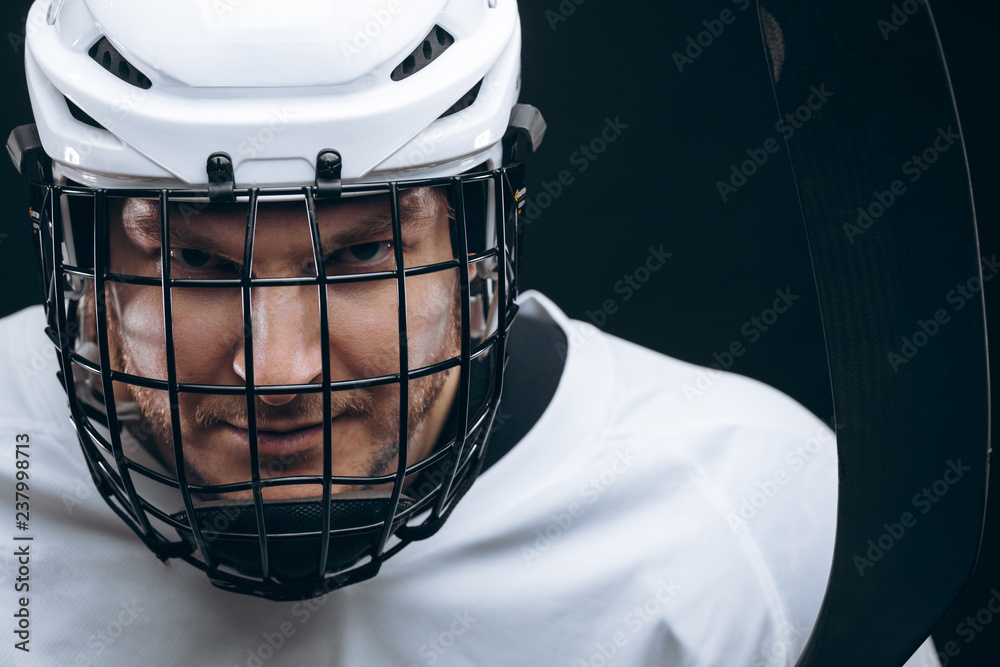 Face portrait of goalkeeper in hockey uniform and protective headgear over black background Face portrait of goalkeeper in hockey uniform and protective headgear over black background