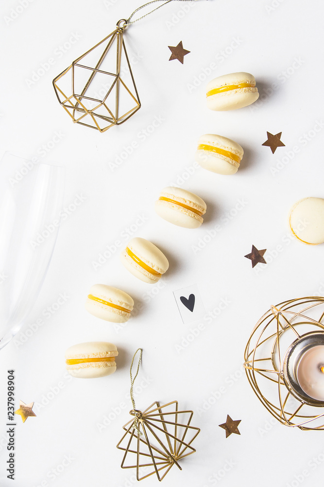 Yellow lemon macaroons on a white background next to champagne glasses. Festive gourmet Christmas aperitif. Top view, flat lay Yellow lemon macaroons on a white background next to champagne glasses. Festive gourmet Christmas aperitif. Top view, flat lay