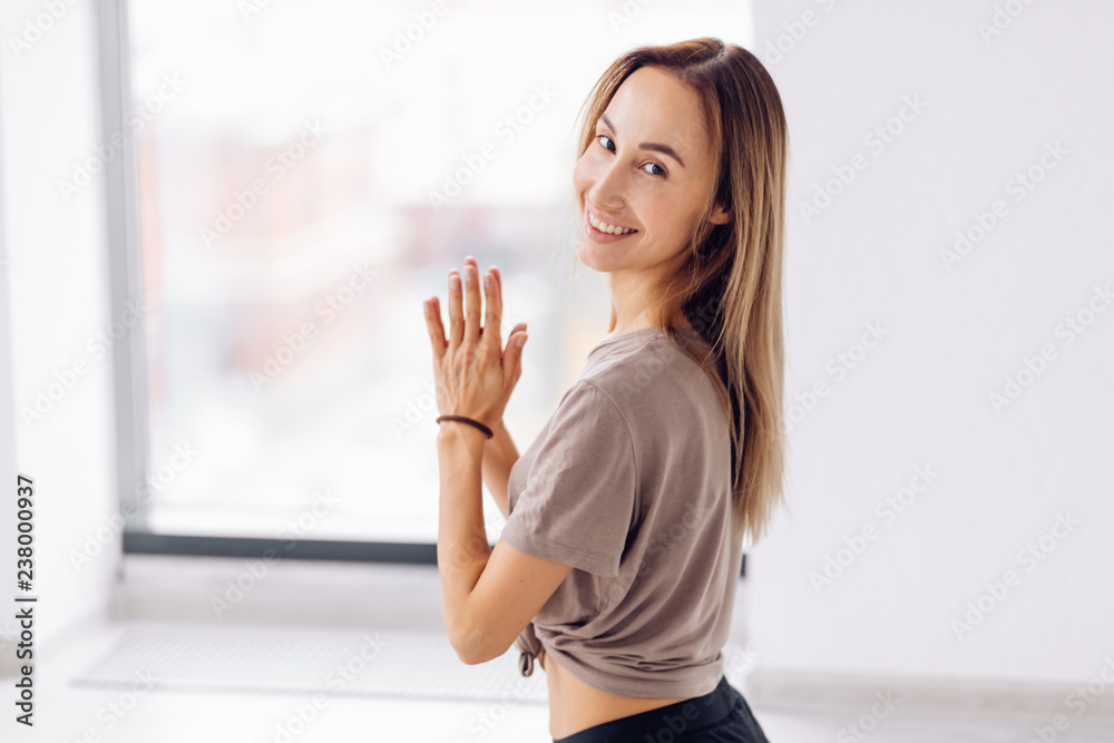 positive optimistic girl performing Namaste gesture and posing to the camera . close up side view photo.