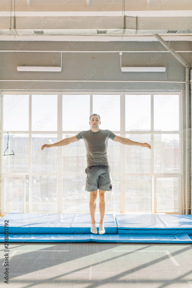 sporty guy is jumping with closed eyes on the trampoline center. full length shot. enjoyment. playful man. sporty guy is jumping with closed eyes on the trampoline center. full length shot. enjoyment. playful man.