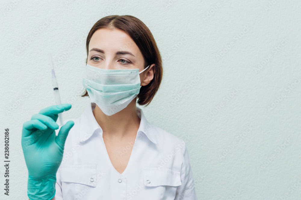 Young female doctor holds a syringe in her hand and looks at it. Concept disease Young female doctor holds a syringe in her hand and looks at it. Concept disease