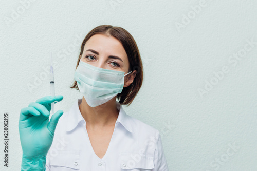 Young woman doctor holds a syringe in her hand. Flu concept