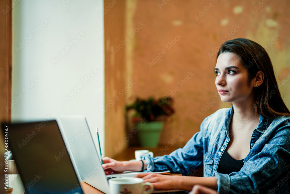 Young female student sits near the window with laptop and look through the window. Young female student sits near the window with laptop and look through the window.