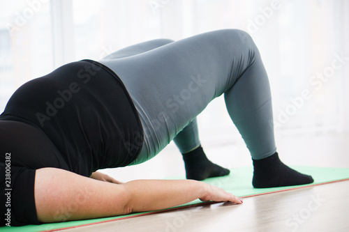 weight loss, fitness, muscular power, perfect shape, flexibility, yoga, pilates. overweight woman doing static bridge exercise to get six-pack abs and strong back