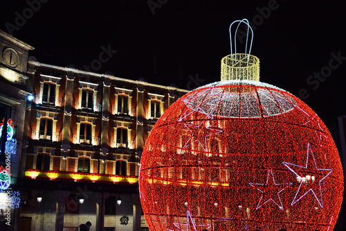 Bola de navidad iluminada y luces de navidad en una plaza.