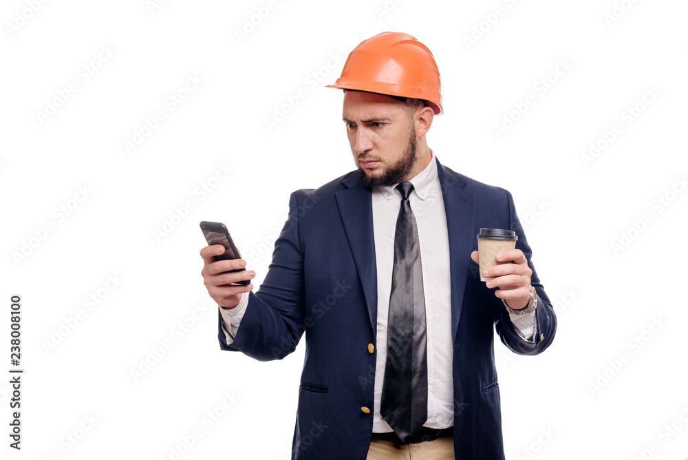 Business portrait of surprised contractor and developer, talking about phone. Businessman in hard hat with cup of coffee standing over white background. News and coffee brake concept Business portrait of surprised contractor and developer, talking about phone. Businessman in hard hat with cup of coffee standing over white background. News and coffee brake concept