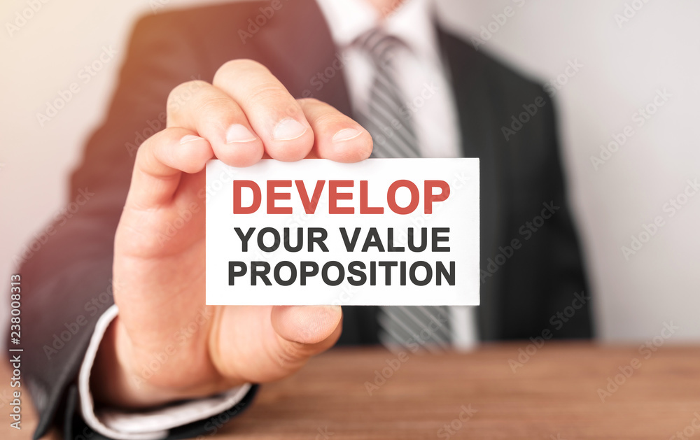 Businessman holding a card with text Develop Your Value Proposition Businessman holding a card with text Develop Your Value Proposition