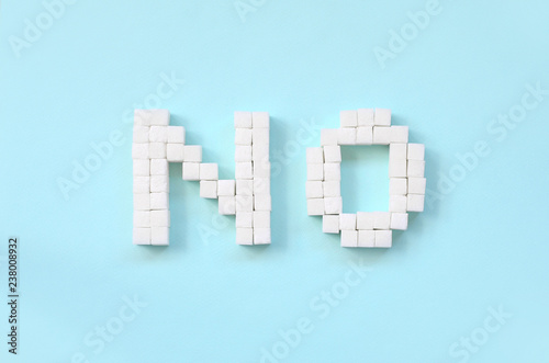 NO Letters of sugar cubes on a pastel blue background. Diabetic concept. Refusing sugar. Flat lay minimal top view photo