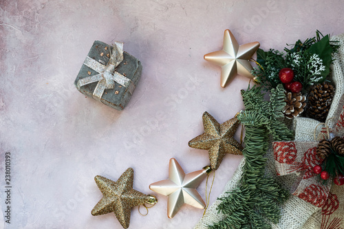 Golden stars, gift box, christmas tree branch and decorations on light pink textured background. Christmas, new year, winter concept. Flat lay, top view, copy space