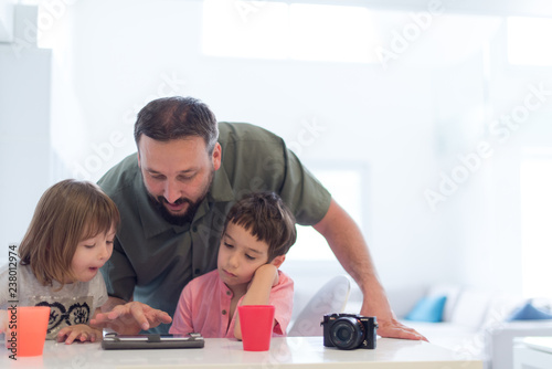 single father at home with two kids playing games on tablet