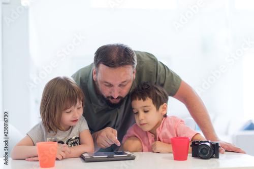 single father at home with two kids playing games on tablet