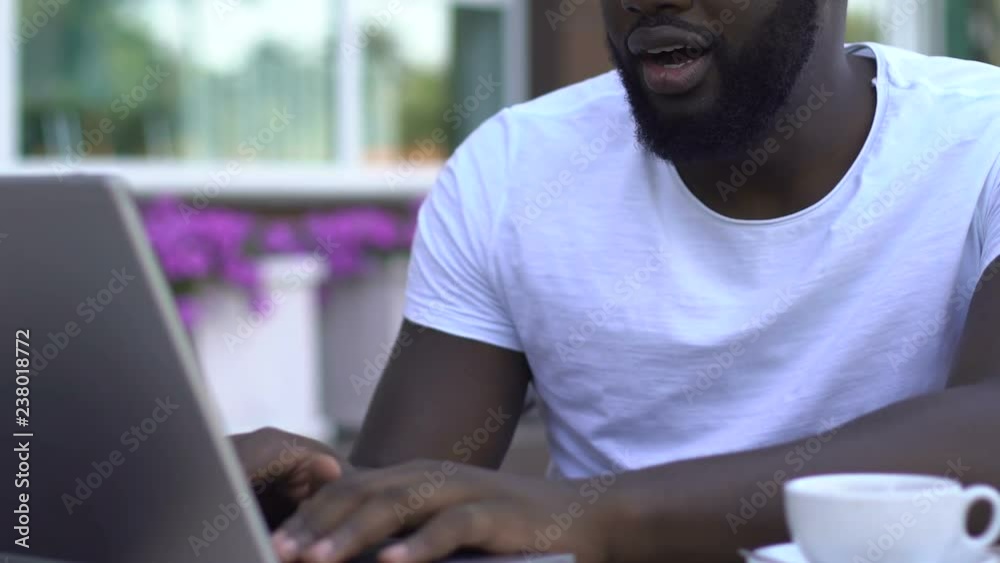 Afro-american man reading e-mail and showing yes gesture, getting promoted Afro-american man reading e-mail and showing yes gesture, getting promoted