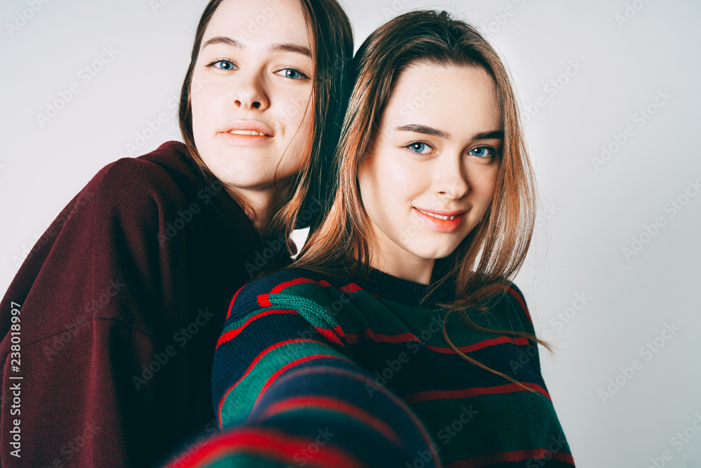 Two sisters twins beautiful girls in casual taking selfie on fro Two sisters twins beautiful girls in casual taking selfie on fro