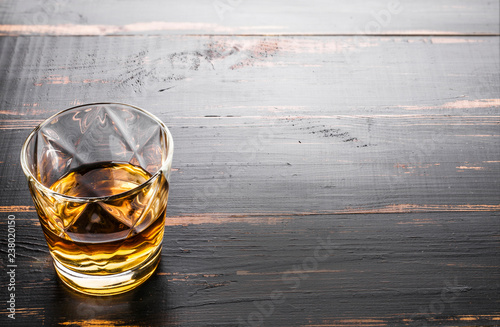 glass of whiskey on dark wooden tabletop