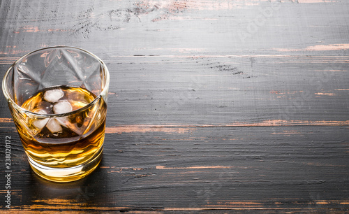glass of whiskey on dark wooden tabletop