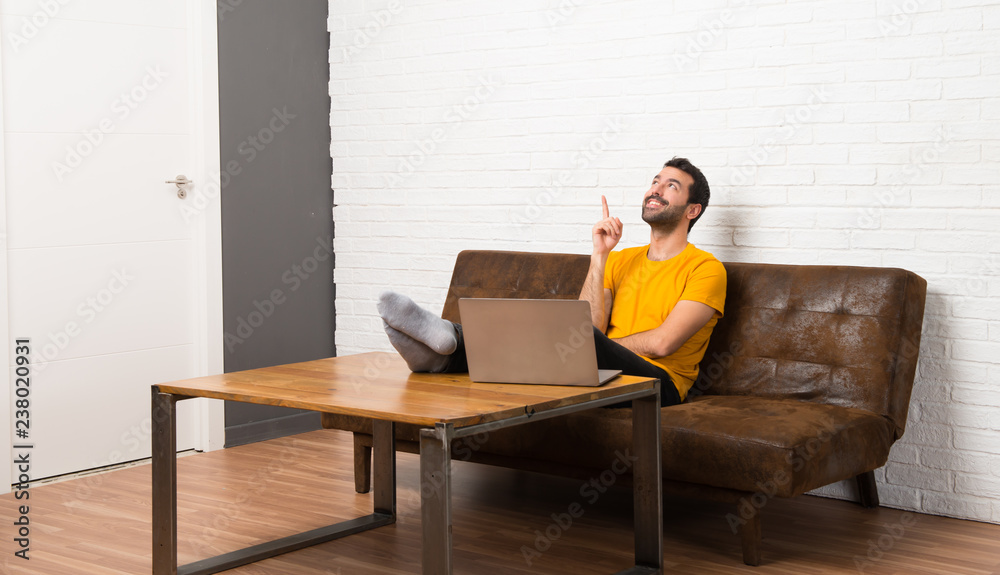 Man with his laptop in a room pointing a great idea and looking up Man with his laptop in a room pointing a great idea and looking up