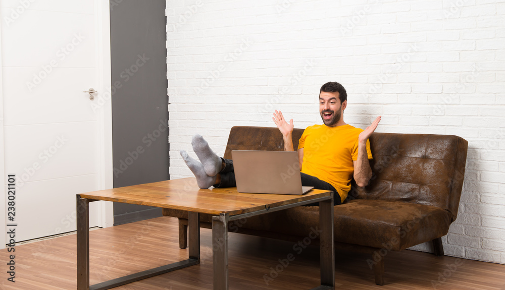 Man with his laptop in a room with surprise and shocked facial expression