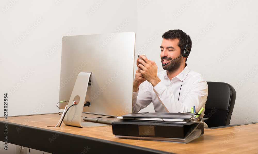 Telemarketer man in a office talking to mobile Telemarketer man in a office talking to mobile