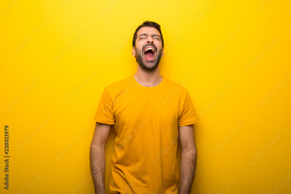 Man on isolated vibrant yellow color shouting to the front with mouth wide open Man on isolated vibrant yellow color shouting to the front with mouth wide open