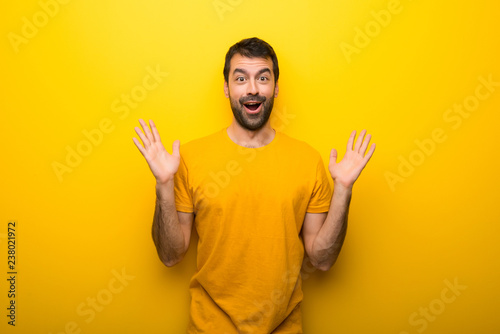Man on isolated vibrant yellow color with surprise and shocked facial expression