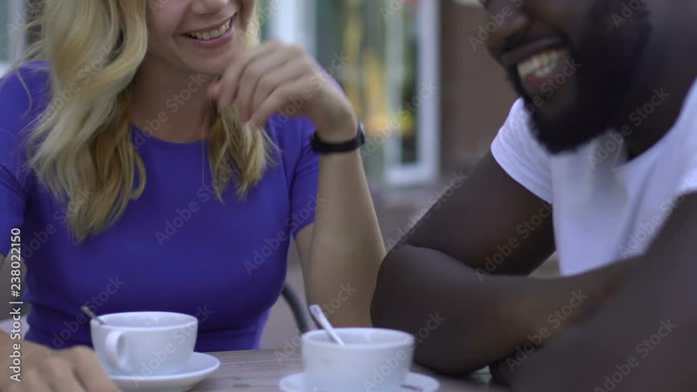 Smiling blond girl flirting with her afro-american boyfriend during date in cafe Smiling blond girl flirting with her afro-american boyfriend during date in cafe