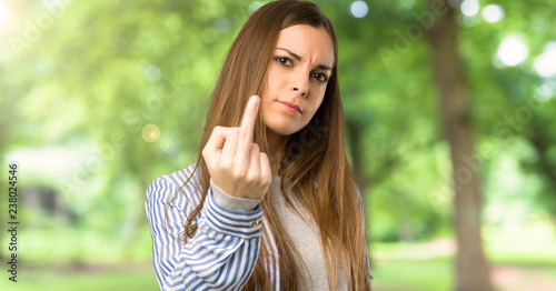 Young girl with striped shirt making horn gesture at outdoors photo