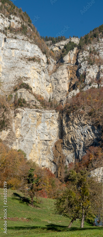 hochformatiges Landschafts-Panorama: hohe Felswand am Walensee mit Wasserfall 