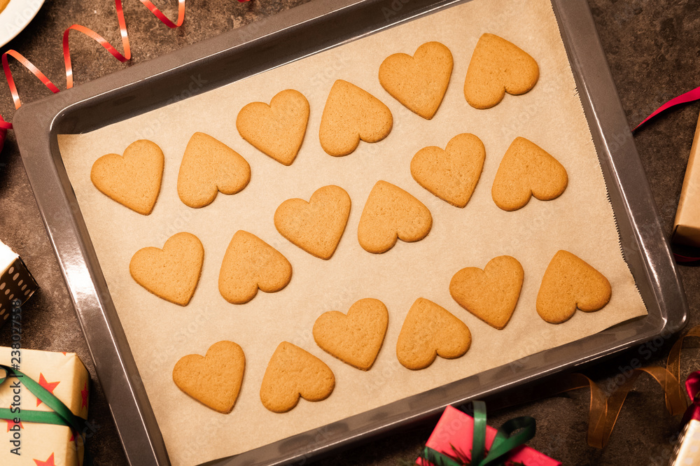 Tasty Christmas cookies on baking tray. Hands hold cookies in form of hear. Tasty Christmas cookies on baking tray. Hands hold cookies in form of hear.