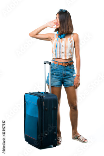 Full body of Girl traveling with her suitcase listening something on isolated white background