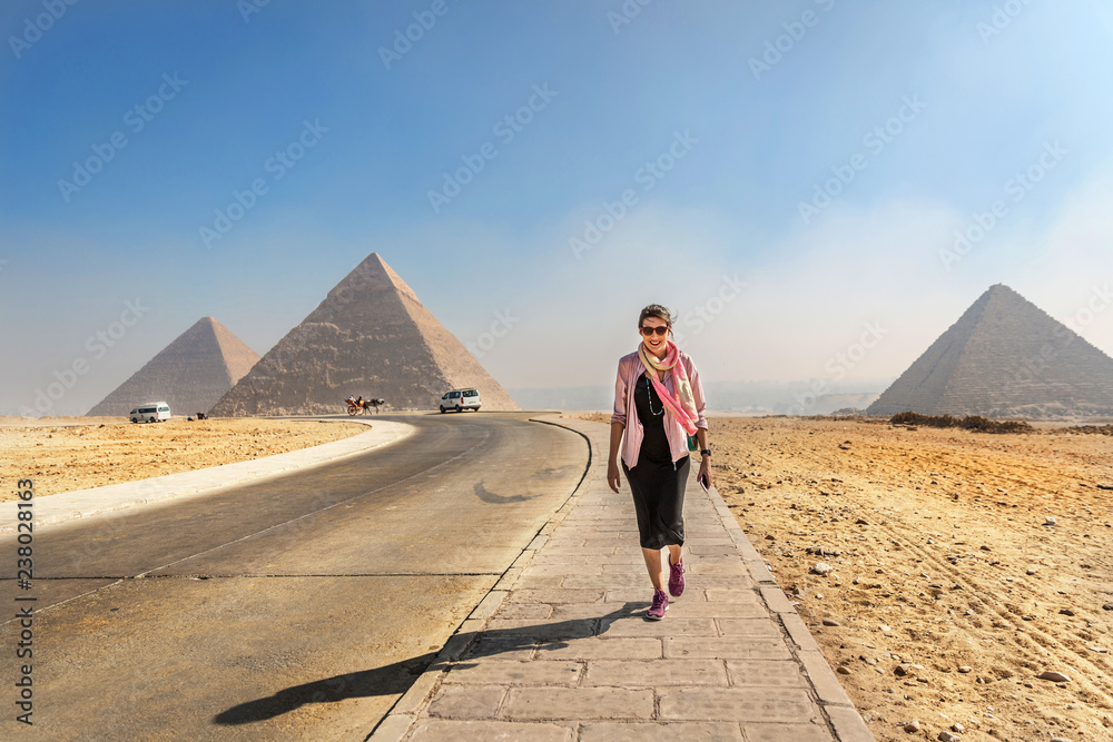 Φωτογραφία Young woman walking in front of the pyramids of Giza in Egypt