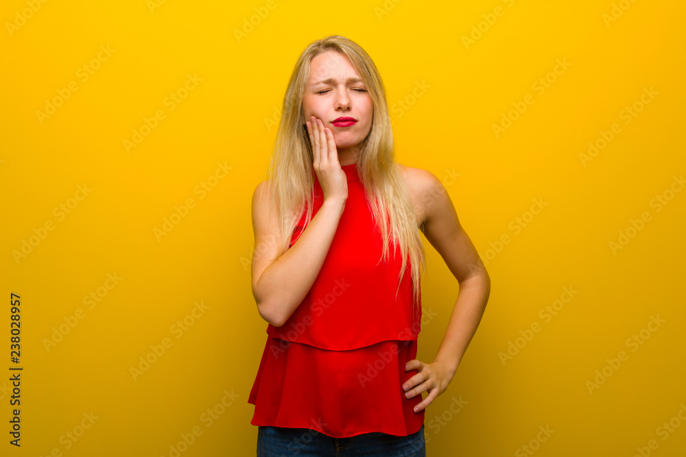 Young girl with red dress over yellow wall with toothache Young girl with red dress over yellow wall with toothache