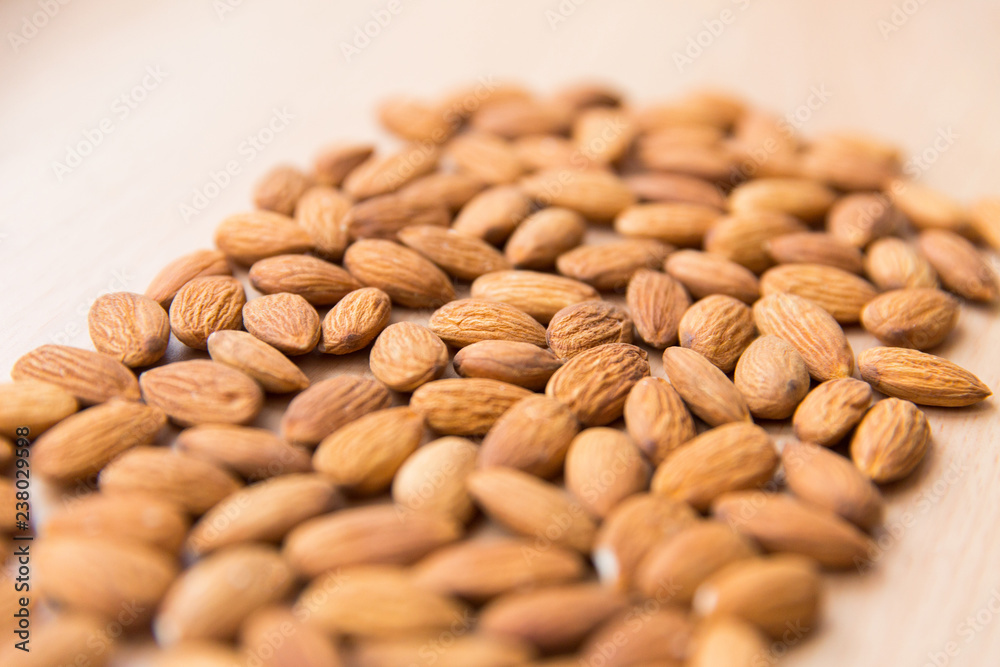 Almond on light wooden table. Texture of almond. Nuts on the table Almond on light wooden table. Texture of almond. Nuts on the table