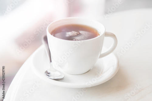 White cu of black tea on white table in the cafe. Breakfast with cup of tea