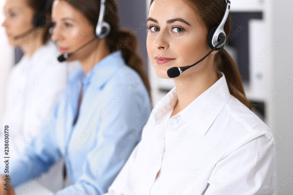 Call center. Group of operators at work. Focus at beautiful business woman in headset Call center. Group of operators at work. Focus at beautiful business woman in headset