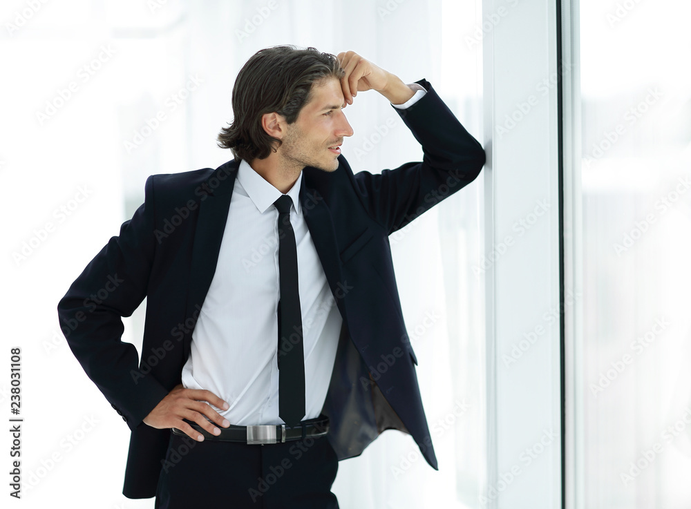 smiling businessman standing near window in office smiling businessman standing near window in office