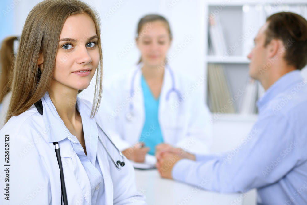 Happy doctor woman with medical staff at the background in hospital office Happy doctor woman with medical staff at the background in hospital office