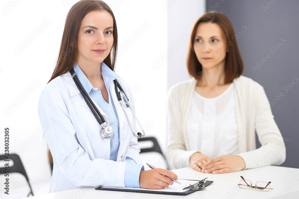 Doctor and patient discussing something while standing near reception desk in emergency hospital. Physician at work in clinic. Medicine and health care concept Doctor and patient discussing something while standing near reception desk in emergency hospital. Physician at work in clinic. Medicine and health care concept