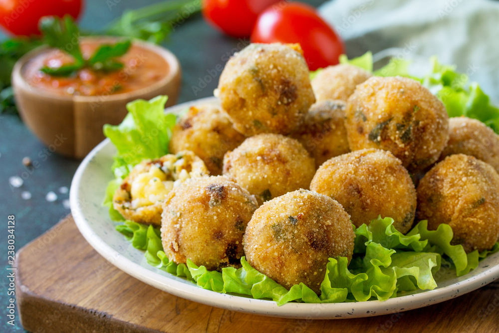 Arancini close-up - traditional Italian Rice Balls with Mozzarella and Sun-dried tomatoes, served with tomato sauce. Arancini close-up - traditional Italian Rice Balls with Mozzarella and Sun-dried tomatoes, served with tomato sauce.