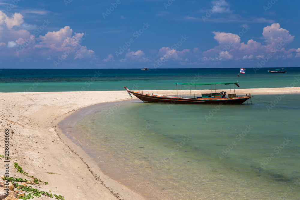 Traditional thai long boat moored at a beach