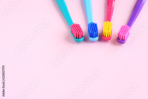 Colorful toothbrushes with selective focus on pink background. Toothbrush for personal routine morning  hygiene on neutral blurred backdrop. Dental plastic tool with empty space for image or text