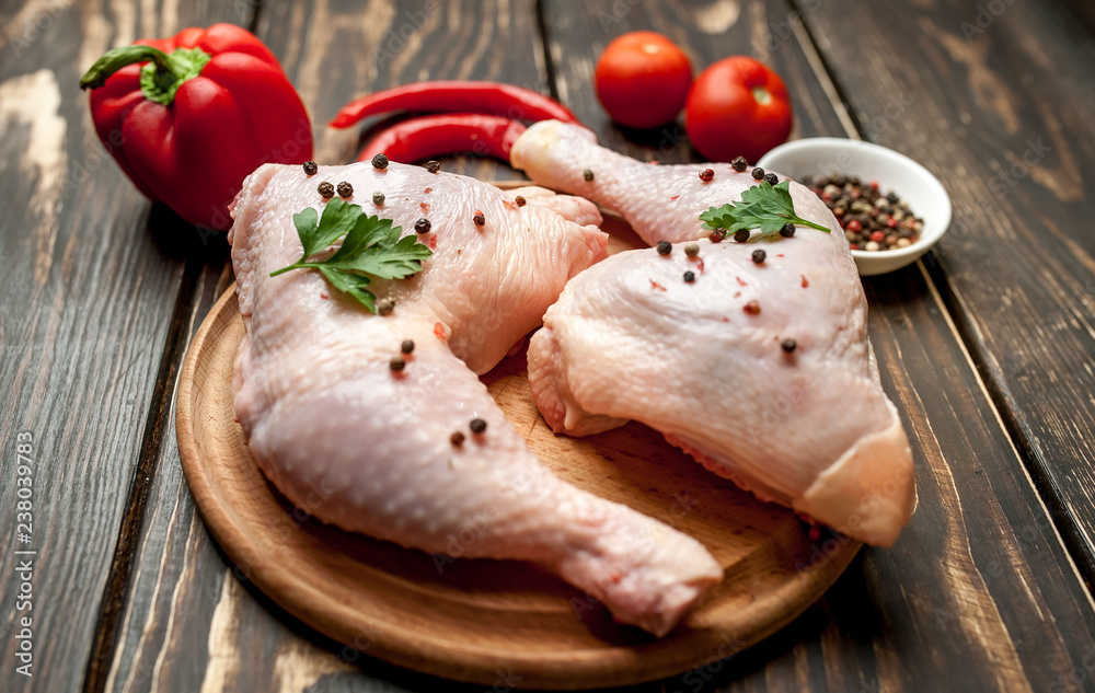 chicken legs with red pepper, tomatoes, parsley on a wooden background chicken legs with red pepper, tomatoes, parsley on a wooden background