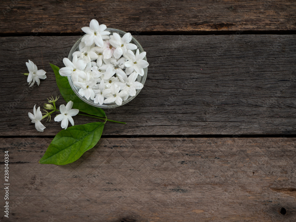 Jasmine floating in clear glass on wooden background. Jasmine floating in clear glass on wooden background.
