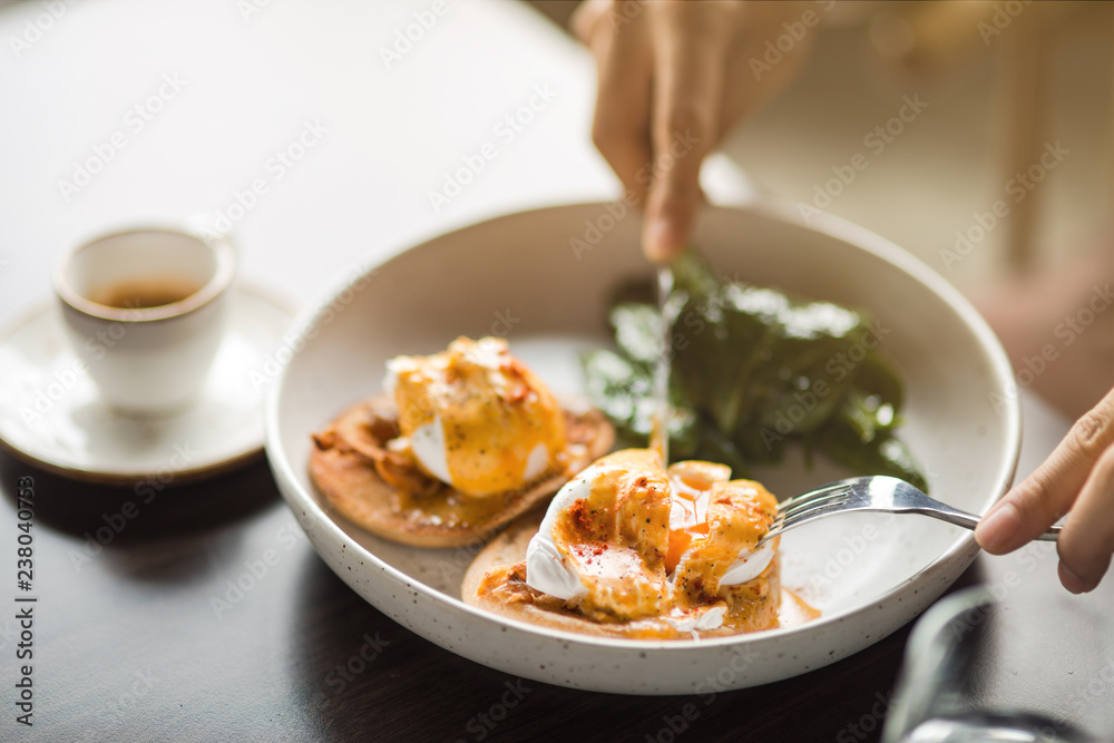 Lunch Time at Cafe. Person eating sandwich with poached egg for lunch drinking espresso table close-up Lunch Time at Cafe. Person eating sandwich with poached egg for lunch drinking espresso table close-up