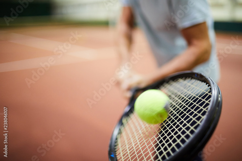 Moving tennis ball being hit by racket in hand of professional player during game