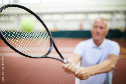Blurred tennis player hitting ball with racket while playing on large stadium or court © pressmaster